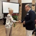 Na zdjęciu jedna z przedstawicielek seniorów wręcza dr. Mirosławowi Radole bukiet czerwonych róż.