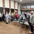 Grupa seniorów wykonuje ćwiczenie - wibrogimnastyka.