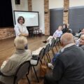 Fizjoterapeutka prowadzi rozmowy z uczestnikami warsztatów.