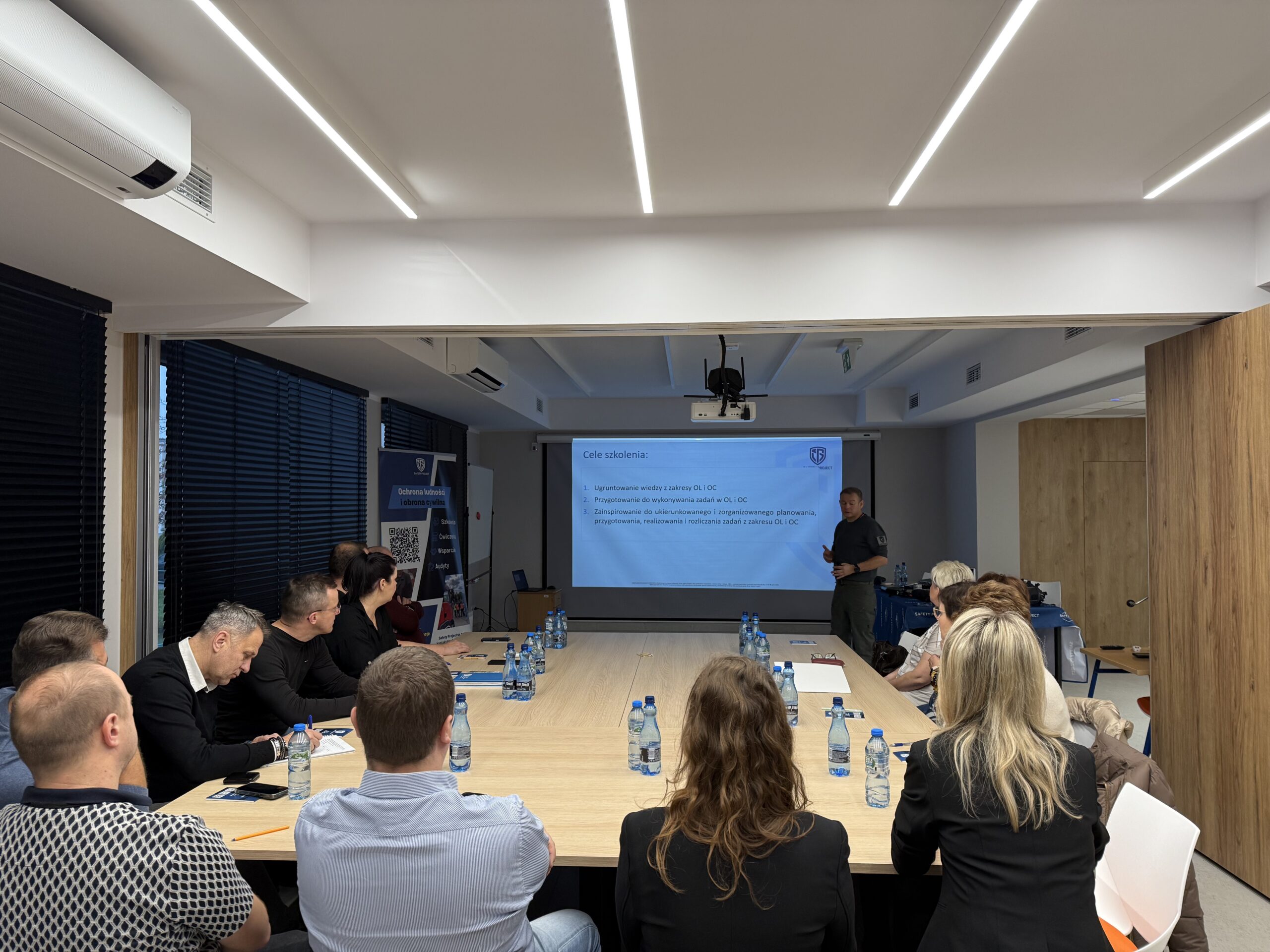 Na fotografii pracownicy urzędu siedzą przy stole i słuchają szkolenia.