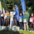 Na zdjęciu zawodnicy z różnych klubów, w tym z klubu Azymut Mochy, stojący na podium. Zawodnicy pozują z medalami i dyplomami.