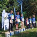 Na zdjęciu zawodnicy z różnych klubów, w tym z klubu Azymut Mochy, stojący na podium. Zawodnicy pozują z medalami i dyplomami.