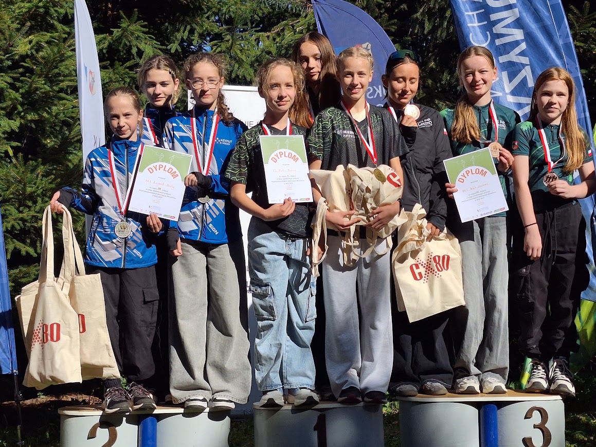 Na zdjęciu zawodnicy z różnych klubów, w tym z klubu Azymut Mochy, stojący na podium. Zawodnicy pozują z medalami i dyplomami.