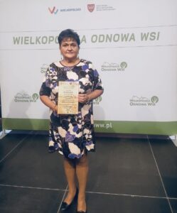 Na zdjęciu sołtys Kaszczoru Beata Binkowska, która pozuje ze statuetką. W tle ścianka Wielkopolska Odnowa Wsi.