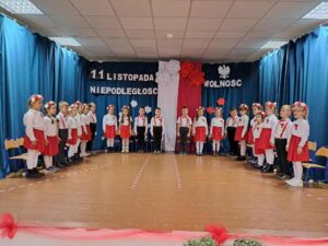 Na zdjęciu grupa przedszkolaków podczas występu na scenie. Wszyscy ubrani są w barwy narodowe.