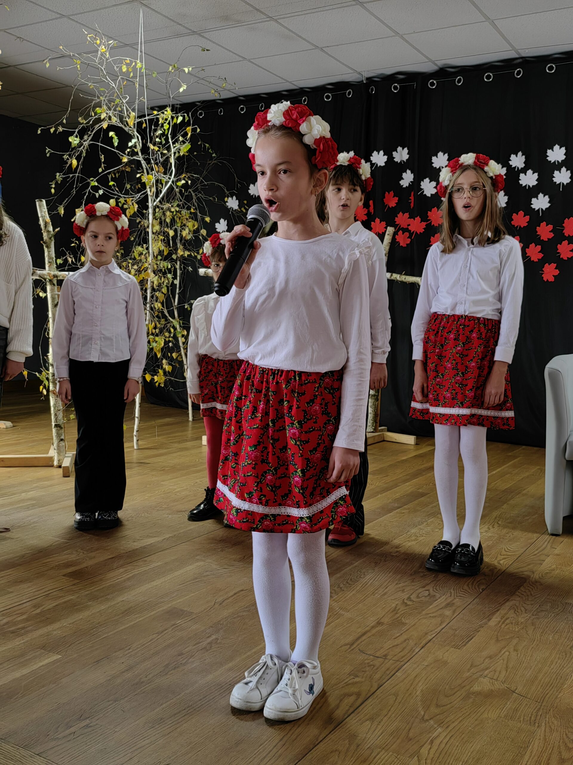 Na zdjęciu uczennica podczas występu artystycznego. W tle inni uczniowie.