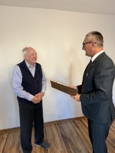 Na fotografii wójt odczytuje życzenia z listu gratulacyjnego jubilatowi.