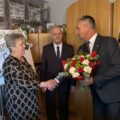 Na zdjęciu wójt gminy, który wręcza bukiet kwiatów jubilatce. W tle jubilat.