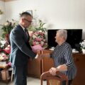 Na zdjęciu widoczny wójt, który składa życzenia jubilatce i wręcza jej bukiet kwiatów.