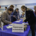 Na zdjęciu widoczne są panie stojące przy stanowisku rejestracji uczestników.