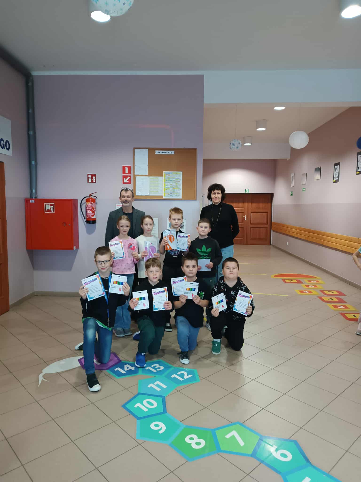 Grupowe zdjęcie dzieci po konkursie z tabliczki mnożenia. Dzieci pozują z dyplomami.