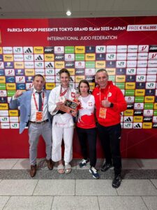 Na zdjęciu Katarzyna Sobierajska wraz ze sztabem trenerskim. Katarzyna pozuje z medalem.