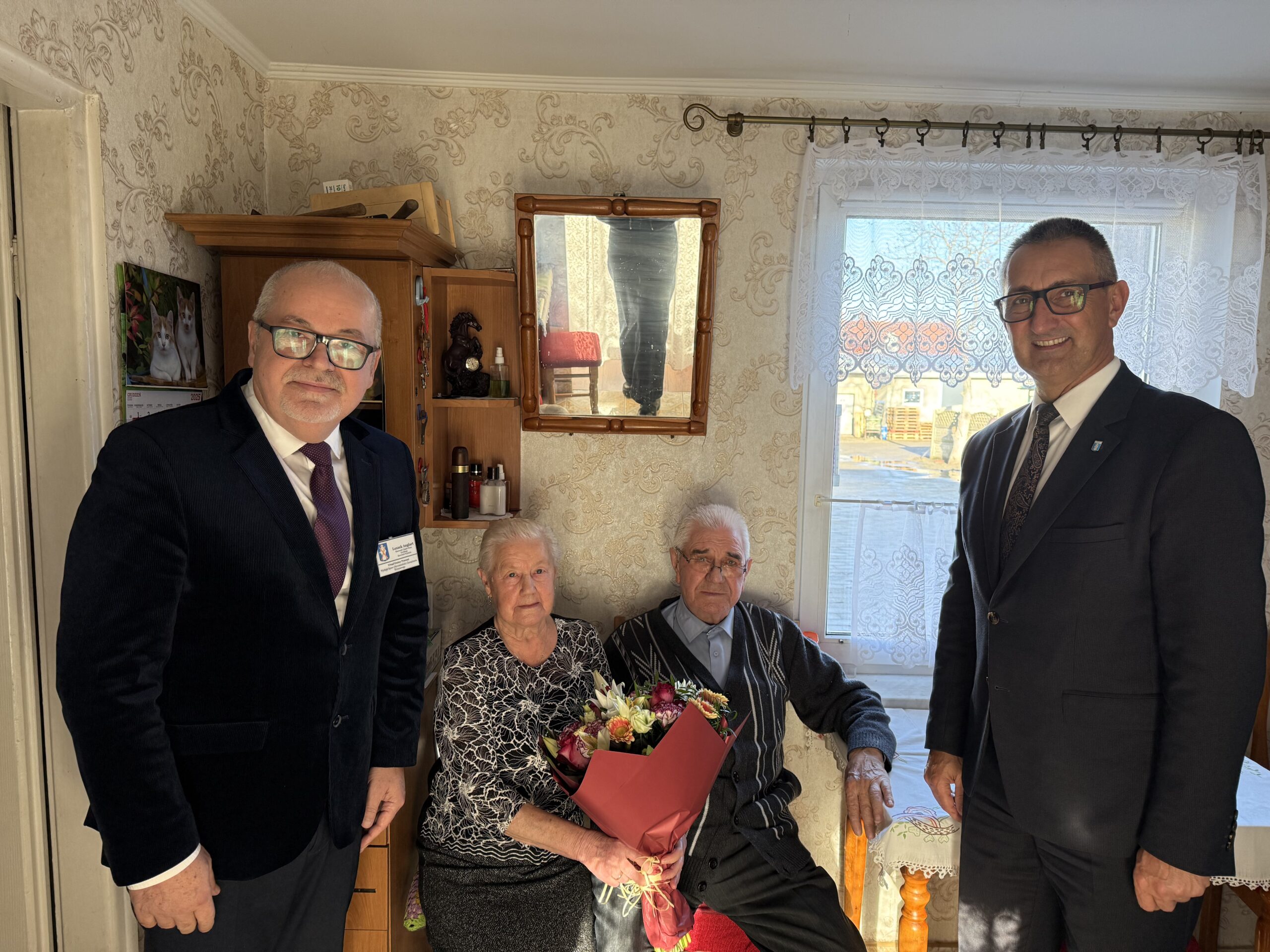 Wspólne zdjęcie, na którym znajdują się wójt, kierownik USC w Przemęcie oraz pan Władysław wraz z małżonką. Jubilat pozuje z bukietem kwiatów.