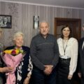 Na zdjęciu wójt Janusz Frąckowiak, pracownik USC Natalia Chomska oraz jubilatka wraz z bliskimi z rodziny. Jubilatka pozuje z bukietem kwiatów.