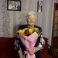 Na zdjęciu jubilatka, która pozuje z bukietem kwiatów.
