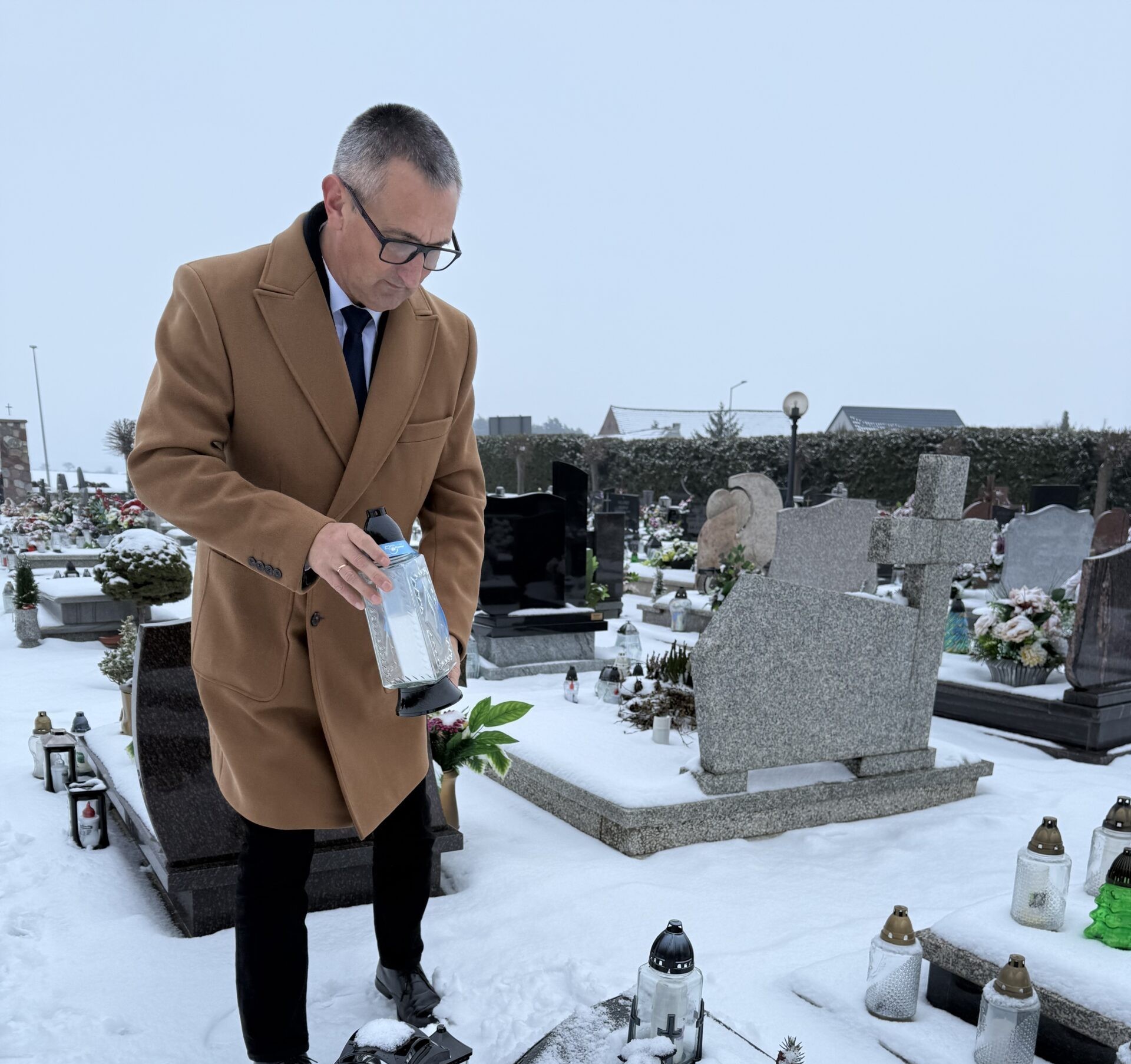 Na zdjęciu wójt składa znicz na grobie osoby zasłużonej dla gminy.