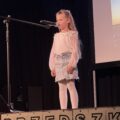 Na fotografii widoczna dziewczynka podczas recytowania wiersza.